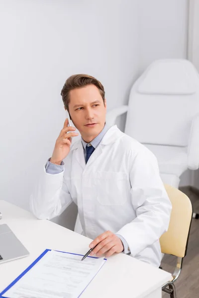 Serious Otolaryngologist Talking Smartphone While Sitting Workplace Clipboard — Stock Photo, Image