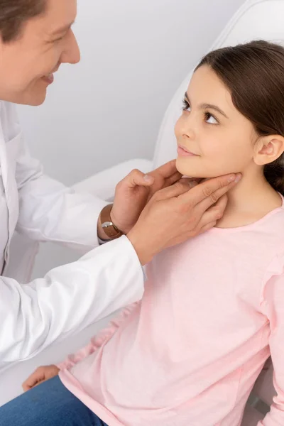 Sonriente Ent Médico Tocando Cuello Lindo Niño Mientras Examina Garganta —  Fotos de Stock