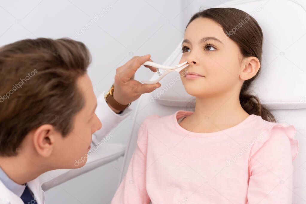 ent physician examining nose of adorable child with nasal speculum