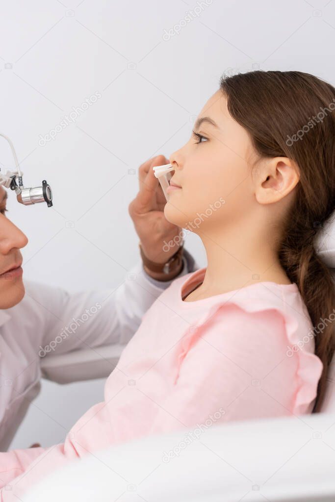 cropped view of ent physician examining nose of adorable child with nasal speculum