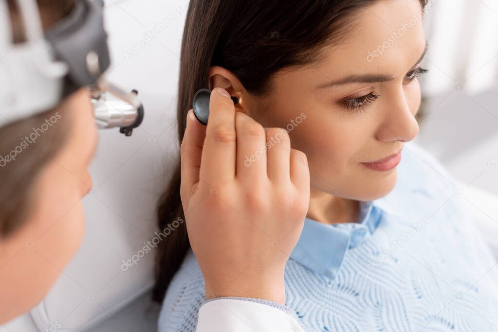 selective focus of otolaryngologist examining ear of attractive patient 