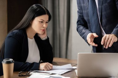 İşadamlarının dizüstü bilgisayarı işaret etmesi ve Asyalı iş kadınının iş görüşmesi sırasında ona bakması. 