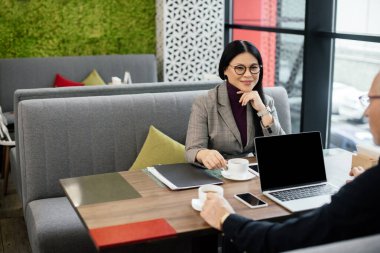 Asyalı bir iş kadınının kafede iş adamıyla konuşmasının seçici odağı.