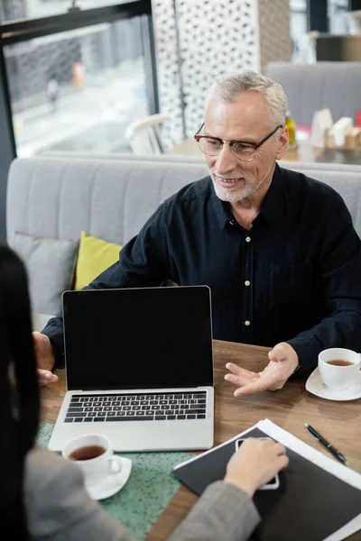 Homem Negócios Sorridente Conversando Com Empresária Sentado Perto Laptop Durante — Fotografia de Stock