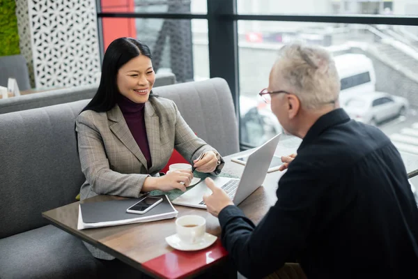 Selektywne Skupienie Się Uśmiechniętej Azjatyckiej Bizneswoman Rozmawiającej Biznesmenem Podczas Spotkania — Zdjęcie stockowe