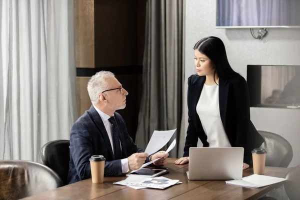 Homem Negócios Segurando Papéis Conversando Com Empresária Asiática Durante Reunião — Fotografia de Stock