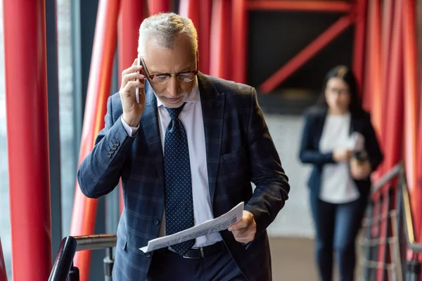 Biznesmen Garniturze Mówi Smartfonie Czyta Gazety — Zdjęcie stockowe