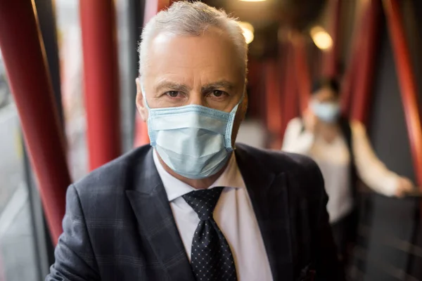 businessman in suit with medical mask looking at camera