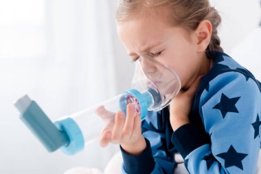 sick kid with closed eyes using inhaler with spacer clipart