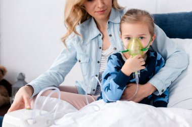 caring mother near asthmatic daughter using compressor inhaler  clipart