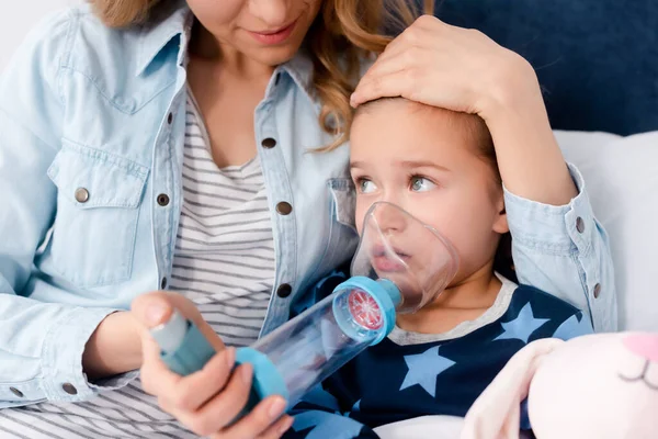 Madre Cariñosa Sosteniendo Inhalador Con Espaciador Cerca Hija Enferma — Foto de Stock