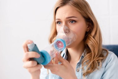 selective focus of asthmatic woman using inhaler with spacer  clipart