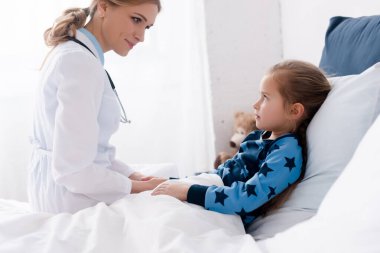 Beyaz önlüklü çekici doktor hasta çocuğa bakıyor. 
