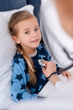 Steteskoplu bir doktorun seçici odağı hasta çocuğu muayene ediyor. 