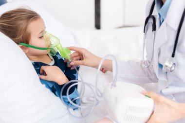 Doktor astımlı çocuğa solunum maskesi takıyor. Kompresör astım spreyi kullanıyor. 