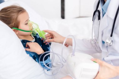 doctor touching respiratory mask on asthmatic kid using compressor inhaler  clipart