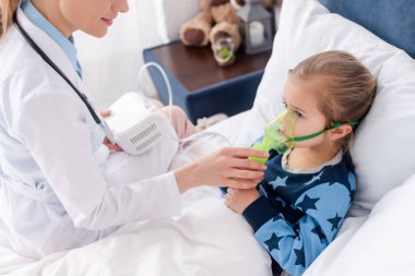 doctor in white coat touching respiratory mask on asthmatic kid using compressor inhaler  clipart