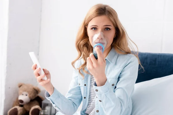 Selective Focus Asthmatic Woman Using Inhaler Spacer Holding Smartphone — Stock Photo, Image