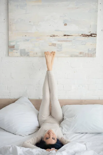 Woman Colorful Hair Raised Legs Looking Camera Smiling Bed Bedroom — Stock Photo, Image