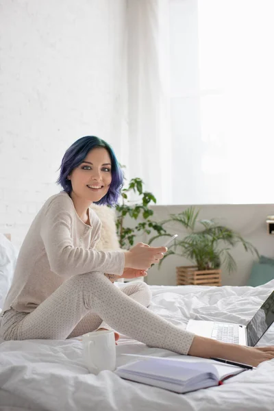 Freelancer Mit Buntem Haar Lächelt Die Kamera Und Nutzt Smartphone — Stockfoto