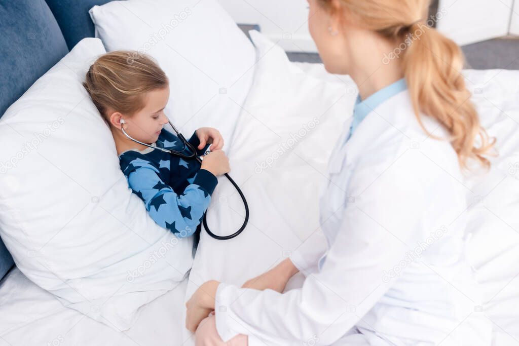 selective focus of sick kid holding stethoscope near doctor 