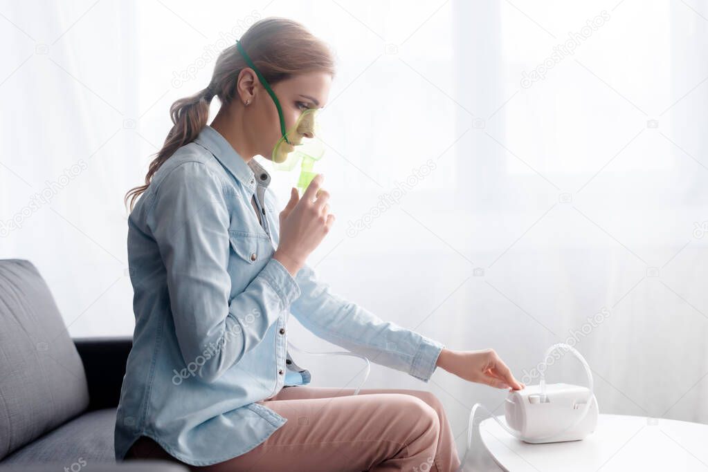 side view of woman in respiratory mask touching compressor inhaler 