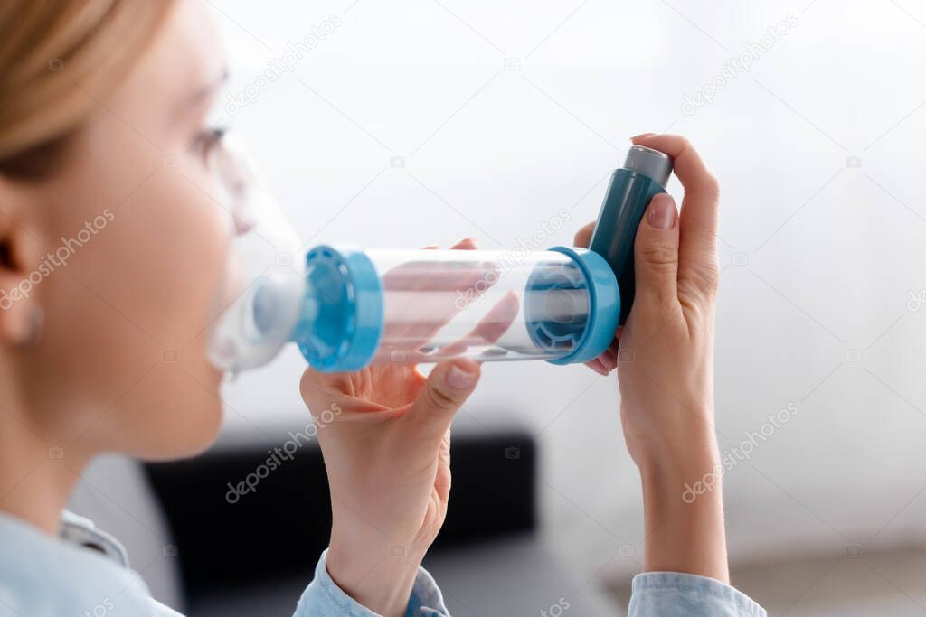 selective focus of asthmatic woman using inhaler with spacer 