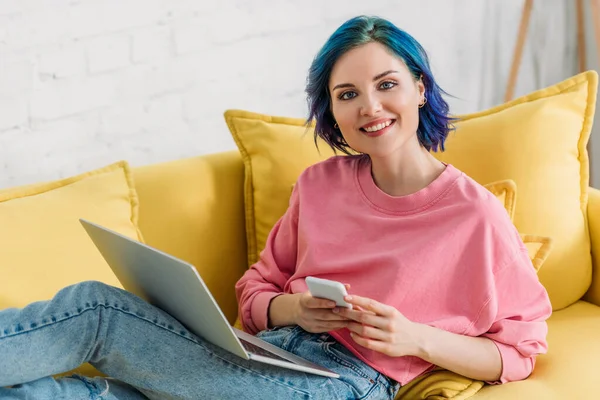 Freelancer Con Cabello Colorido Portátil Sosteniendo Smartphone Sonriendo Mirando Cámara —  Fotos de Stock