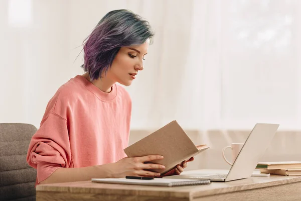 Freelancer Com Livro Leitura Cabelo Colorido Perto Laptop Mesa Sala — Fotografia de Stock