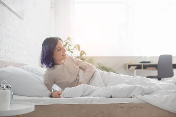 Renkli Saçlı Gülümseyen Yatakta Uzanan Bir Kadın — Stok fotoğraf