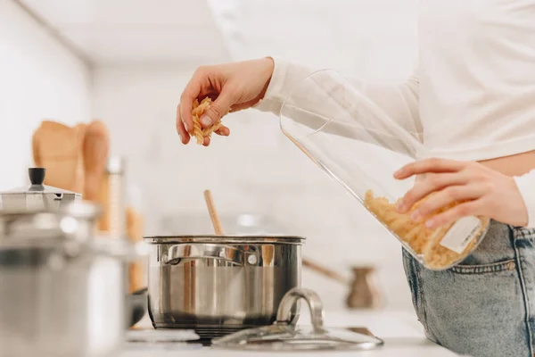 Cropped view of girl putting pasta in pan near kitchen stove — Stock Image Cropped View Girl Putting Pasta Pan Kitchen Stove Royalty Free Stock Photos