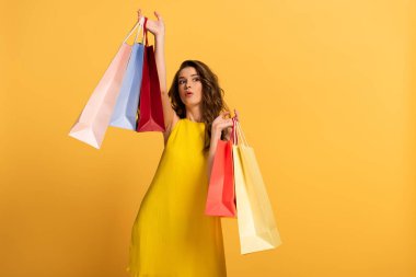 Sarı elbiseli sürpriz kız alışveriş torbaları taşıyor.