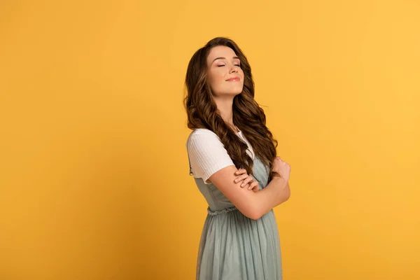 happy spring girl with crossed arms on yellow