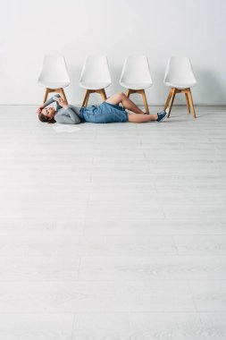 Ofiste yerde yatarken akıllı telefon kullanan çekici bir çalışanın düşük açılı görüntüsü 