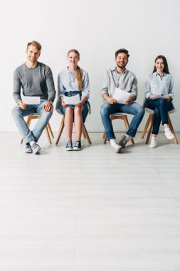 Ofiste kameraya gülümseyen bir grup genç çalışan. 