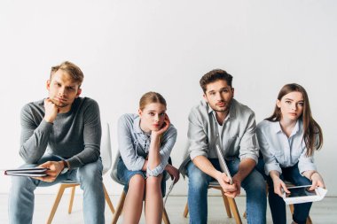 Özgeçmişi ve cihazları olan bir grup genç aday ofiste kameraya bakıyor. 