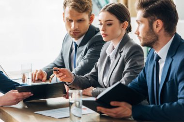 Selective focus of recruiters looking at employee showing clipboard during job interview  clipart