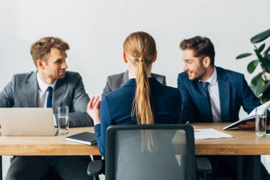 Ofisteki gülümseyen acemilerin yanında oturan çalışanların seçici odağı 
