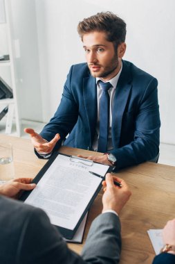 Takım elbiseli çalışanın seçici odağı özgeçmişi masada olan işe alım görevlisine bakıyor.