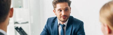 Selective focus of employee looking at recruiter in office, panoramic shot  clipart