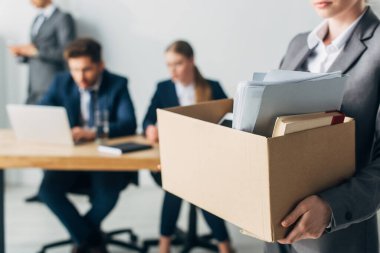Seçici odak noktası, kovulmuş bir kadının elinde kitap ve kağıtlarla dolu bir kutu tutması. 