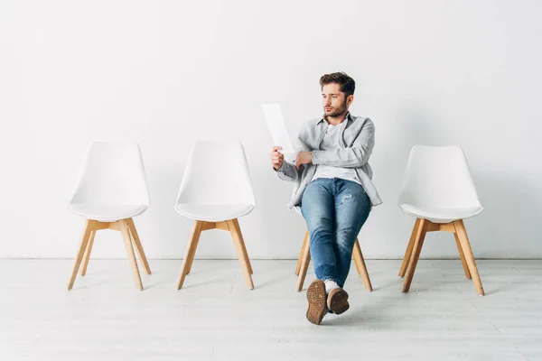 Schöner Mann Schaut Auf Lebenslauf Während Auf Stuhl Büro Sitzt — Stockfoto