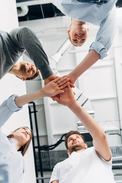Bottom view of smiling colleagues holding hands in office 