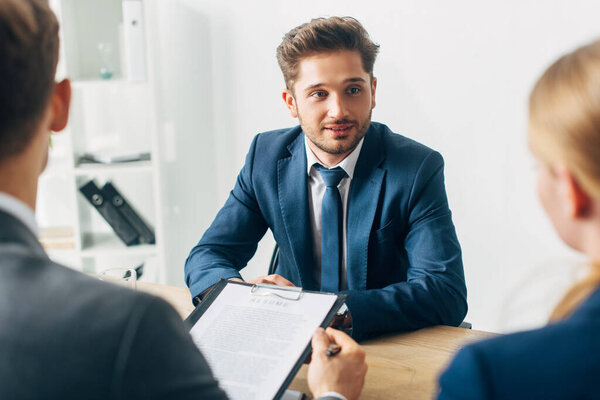 Selective focus of handsome employee looking at recruiter during job interview