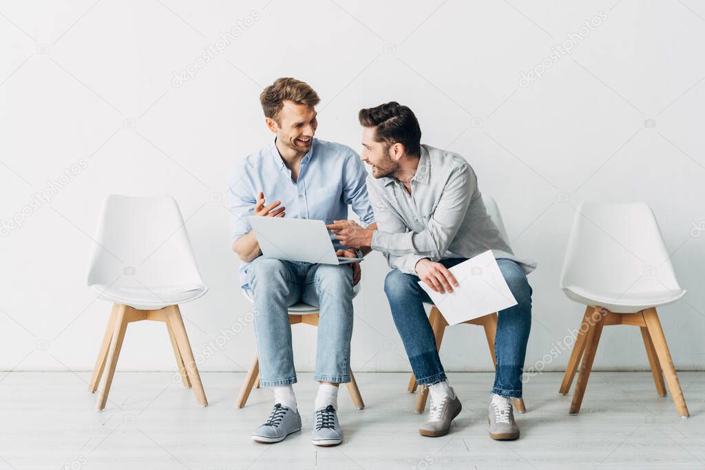 Smiling candidates with laptop and resume waiting for job interview in office