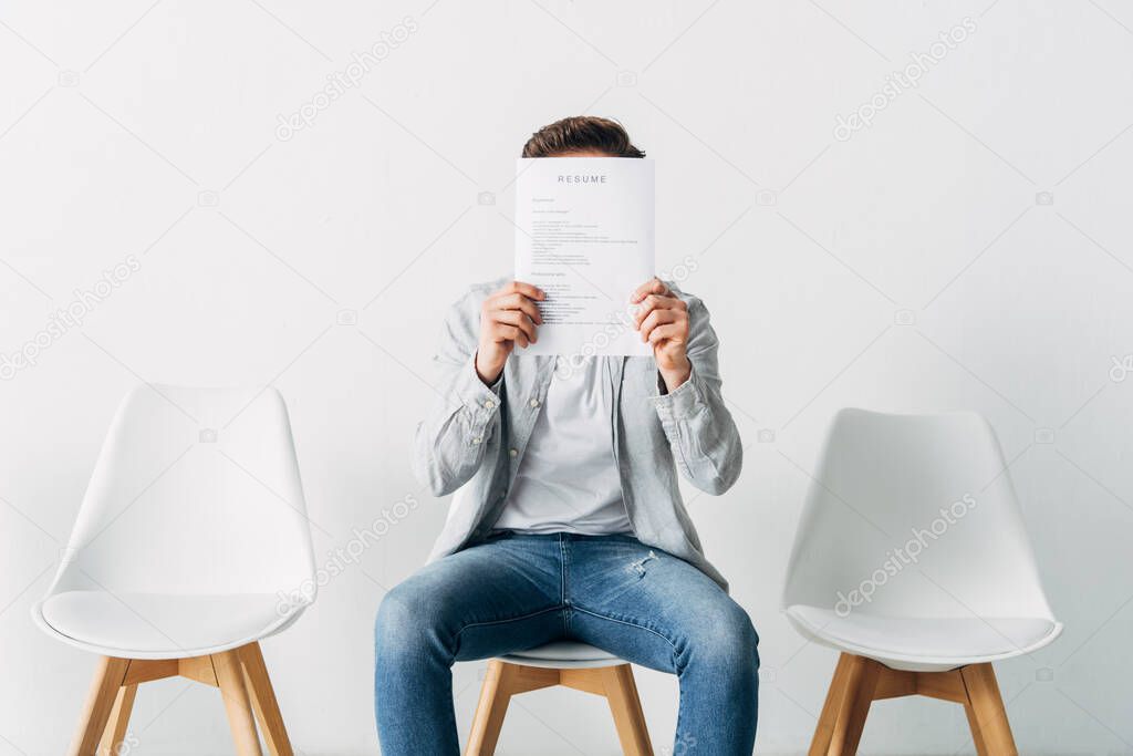 Man covering face with resume in office