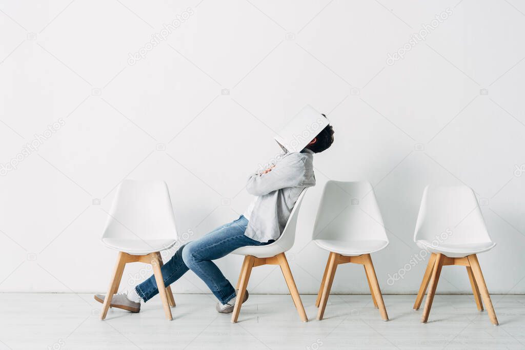 Side view of employee with crossed arms covering face with laptop on chair