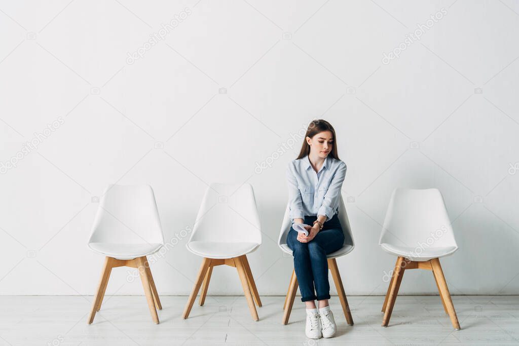 Beautiful employee with resume sitting on chair in office 