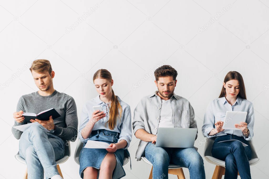 Employees using digital devices while waiting for job interview in office 