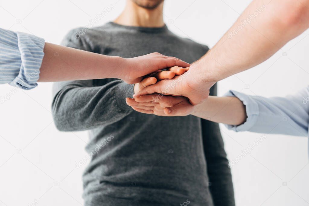 Cropped view of coworkers holding hands in office 